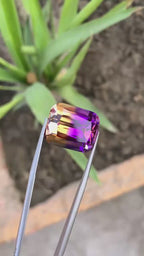 ametrine gemstone held by tweezers with a green background